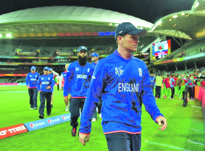 ELIMINATED: Eoin Morgan leads a dejected looking England side off the field after defeat to Bangladesh
