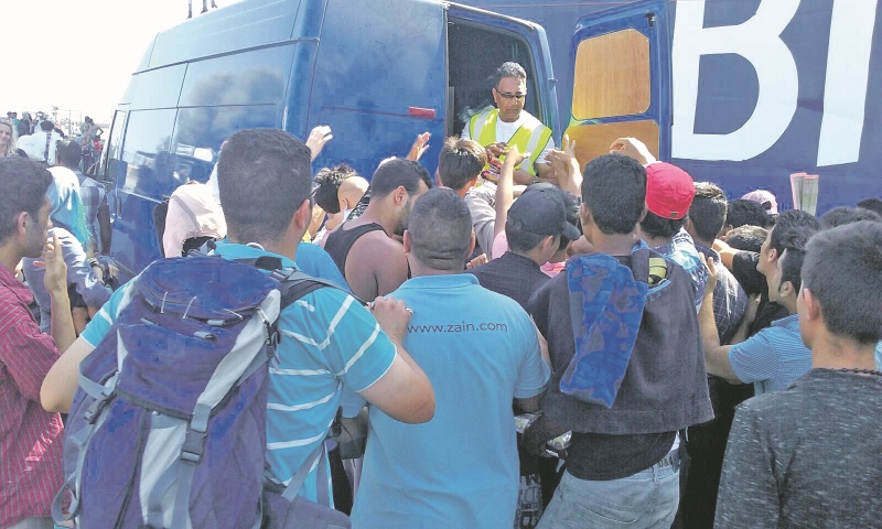 SUPPLIES: Refugees crowd around the van as supplies are handed out by Ghalib, Abdul and Shafiq