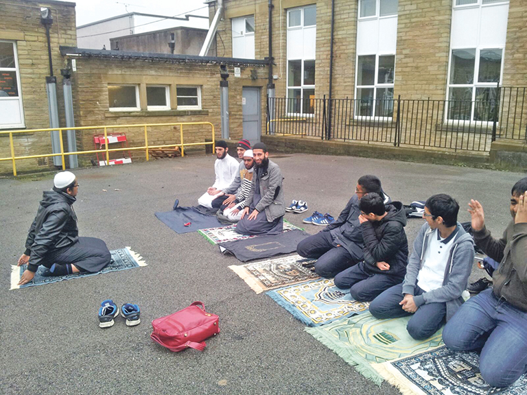 FAITH: Children conduct prayers in the playground after being told there are no facilities inside