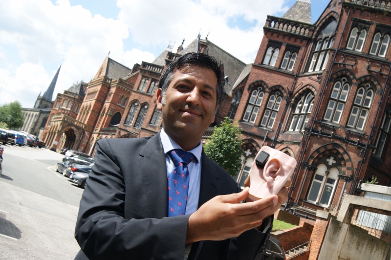 EAR HERO: Consultant ENT surgeon Dr Verma stands outside the red granite bricks of Leeds General Infirmary with an anatomical model showing a BAHA hearing aid